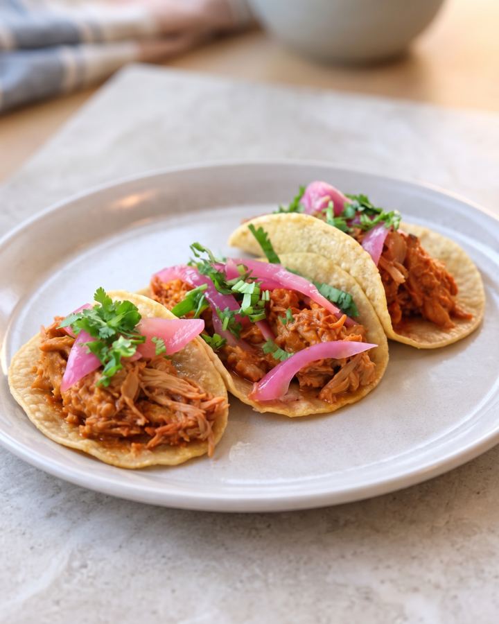 Three tacos with pickled onion